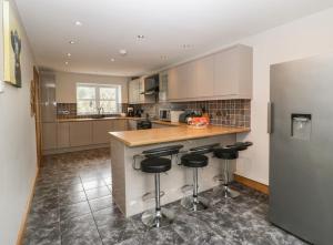 a kitchen with a counter and bar stools at About Time Cottage in Lydney