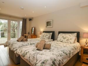 a bedroom with two beds and a window at About Time Cottage in Lydney