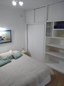 a white bedroom with a bed and shelves at Inmejorable ubicación frente al mar in Puerto Madryn