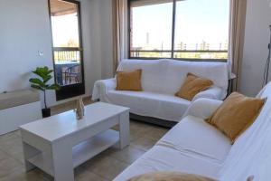 ein Wohnzimmer mit einem weißen Sofa und einem Tisch in der Unterkunft Playa Mucha Vista apto, Parking, Piscina, AC in El Campello