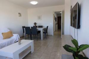 ein Wohnzimmer mit einem Sofa und einem Tisch mit Stühlen in der Unterkunft Playa Mucha Vista apto, Parking, Piscina, AC in El Campello