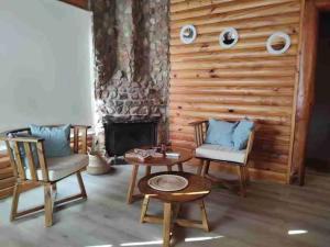 sala de estar con 2 sillas, mesa y chimenea en Balcon del Golf en Sierra de la Ventana