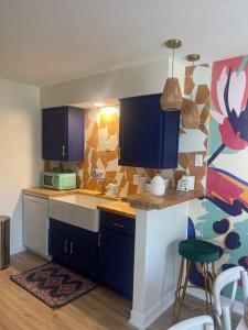 a kitchen with blue cabinets and a colorful wall at Luv Happii House in Country Club Hills