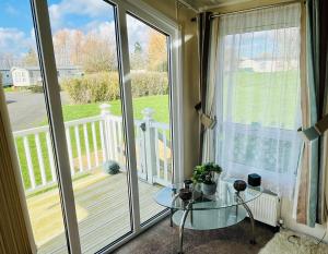 a room with a glass table and a balcony at 40A Oak Village- 2 Bedroom Lodge on Grange Leisure Park in Mablethorpe