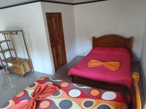 Casa Osa Azul في بويرتو خيمينيز: غرفة نوم بسرير مع مفرش وردي مع ربطه قوس