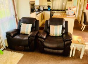 a living room with two leather chairs and a table at 40A Oak Village- 2 Bedroom Lodge on Grange Leisure Park in Mablethorpe