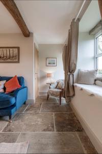 Bents Holiday Cottage في Oxenhope: غرفة معيشة مع أريكة زرقاء وكرسي