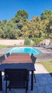 einen Tisch und Stühle vor einem Pool in der Unterkunft Maison Moderne Piscine Bordeaux in Pessac