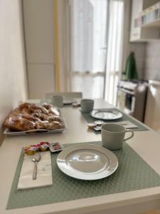 einen Tisch mit Tellern und Tassen sowie ein Tablett mit Gebäck in der Unterkunft Appartamento da Marietta in Tivoli Terme