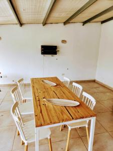 a wooden table with white chairs around it at Chalet con pileta y quincho, hermoso jardín in Tandil
