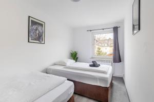 two beds in a room with a window at 44 Apartments - Modern, Gemütlich, WLAN, Balkon, Stellplatz in Wuppertal