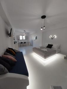 a white living room with a bed and a couch at East Wind Perissa in Perissa