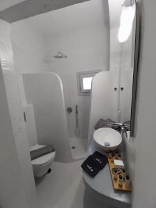 a white bathroom with a sink and a toilet at East Wind Perissa in Perissa