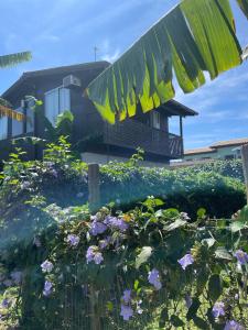 a house with a bunch of flowers in front of it at Casas Paz e Amor Praia do Rosa Sunset e Sunrise in Imbituba