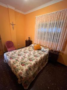 una camera da letto con un letto con copriletto fiorito e una finestra di Casa Rural Los Tilos Betancor a Moya