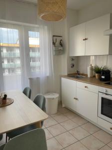 uma cozinha com armários brancos e uma mesa com cadeiras em Nordsee FeWo em Bremerhaven