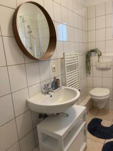 uma casa de banho com um lavatório, um espelho e um WC. em Nordsee FeWo em Bremerhaven