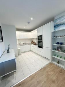 a kitchen with white cabinets and a white tile floor at Elegant 2 Bedroom Apartment in Grand Canal in Dublin