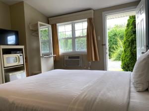 Un dormitorio con una gran cama blanca y una ventana en Motel des Cèdres, en Sherbrooke
