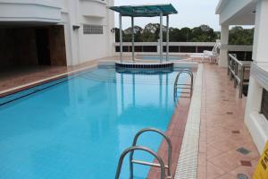 a swimming pool with chairs and an umbrella on a building at Parkview Hotel in Kampong Jerudong