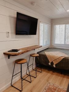 a bedroom with a bed and two stools and a tv at Shipping Container Home near Fall Creek Falls State Park in Dunlap