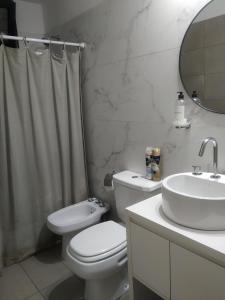 a white bathroom with a toilet and a sink at Casa 4 amb y cochera Don Bosco in Córdoba