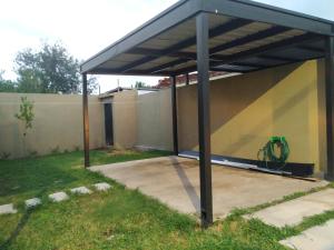 a garage with a metal roof on a yard at Casa 4 amb y cochera Don Bosco in Córdoba