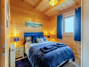 a bedroom with a blue bed in a wooden room at Seashell Lodge in Gairloch