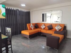 ein Wohnzimmer mit einem orangenen Sofa und einem Spiegel in der Unterkunft Apartamentos "APPART D'ELIETTE" in Trujillo