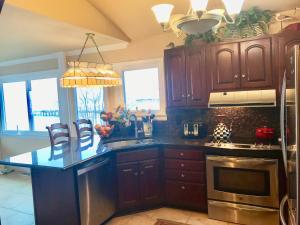 a kitchen with wooden cabinets and a sink and a stove at Chesapeake Bay Maryland Waterfront Home, Stunning Views 45 min from DC pier fossils hiking in Port Republic