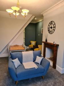 a living room with a blue couch and a table at Stunning River View in Mytholmroyd