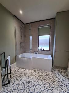 baño grande con bañera y ventana en Stunning River View, en Mytholmroyd