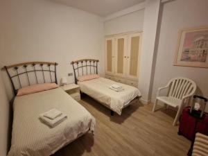a bedroom with two beds and a chair and a suitcase at Estepona playa in Estepona
