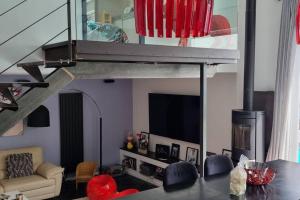 a living room with a couch and a tv and a table at Magnifique maison d'architecte Bordeaux Mérignac in Mérignac