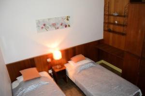 a bedroom with two beds and a lamp on the wall at Résidence LA GRIFOULLIÈRE - Maisons & Villas pour 6 Personnes 74 in Port Leucate