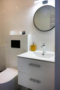 W białej łazience znajduje się umywalka i lustro. w obiekcie Industrial Kato w mieście Katowice