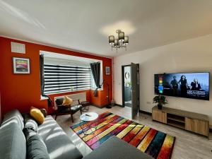 a living room with a couch and a flat screen tv at Sandringham House - Serene Escape Cottage in Cleethorpes