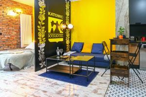een woonkamer met een blauwe bank en een gele muur bij Industrial Kato in Katowice