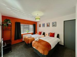 two beds in a room with orange walls at Sandringham House - Serene Escape Cottage in Cleethorpes