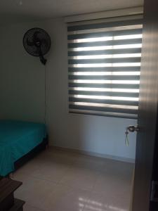 1 dormitorio con ventana con persianas y ventilador en Hospédate cerca al aeropuerto Matecaña, en Pereira