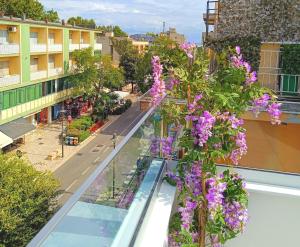 a balcony with purple flowers on a city street at Residenza delle Nazioni in Gatteo a Mare