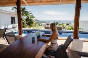 een vrouw aan een tafel met een laptop bij Lodge Las Estrellas de Samara in Sámara