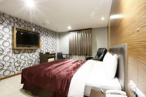 een hotelkamer met een bed en een flatscreen-tv bij Hua Xiang Motel - Arena in Kaohsiung