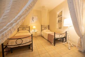 Un dormitorio con dos camas y una lámpara. en Maison Elirè - 10 passi dal mare, en Capoliveri