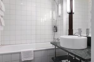 La salle de bains blanche est pourvue d'un lavabo et d'une baignoire. dans l'établissement Elite Park Avenue Hotel, à Göteborg