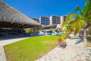 a resort with a park with palm trees and a playground at Coral Blue Huatulco All Inclusive in Santa Cruz Huatulco