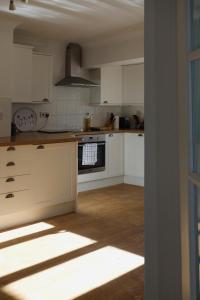 a kitchen with white cabinets and a stove top oven at 10 Yards from Sea Hightide – Own Access to Beach in Sheringham