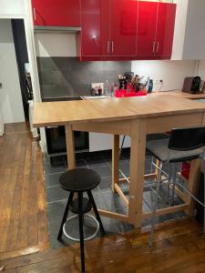 een keuken met een houten tafel en rode kasten bij Apt 4personnes idéal pour les JO in Boulogne-Billancourt