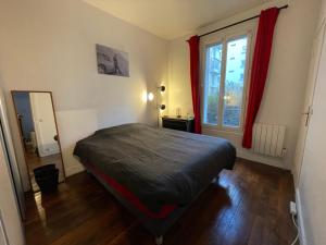 een slaapkamer met een bed en een raam met rode gordijnen bij Apt 4personnes idéal pour les JO in Boulogne-Billancourt