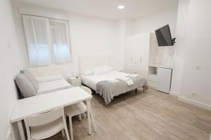 a white room with two beds and a tv at Pension MD in San Sebastián